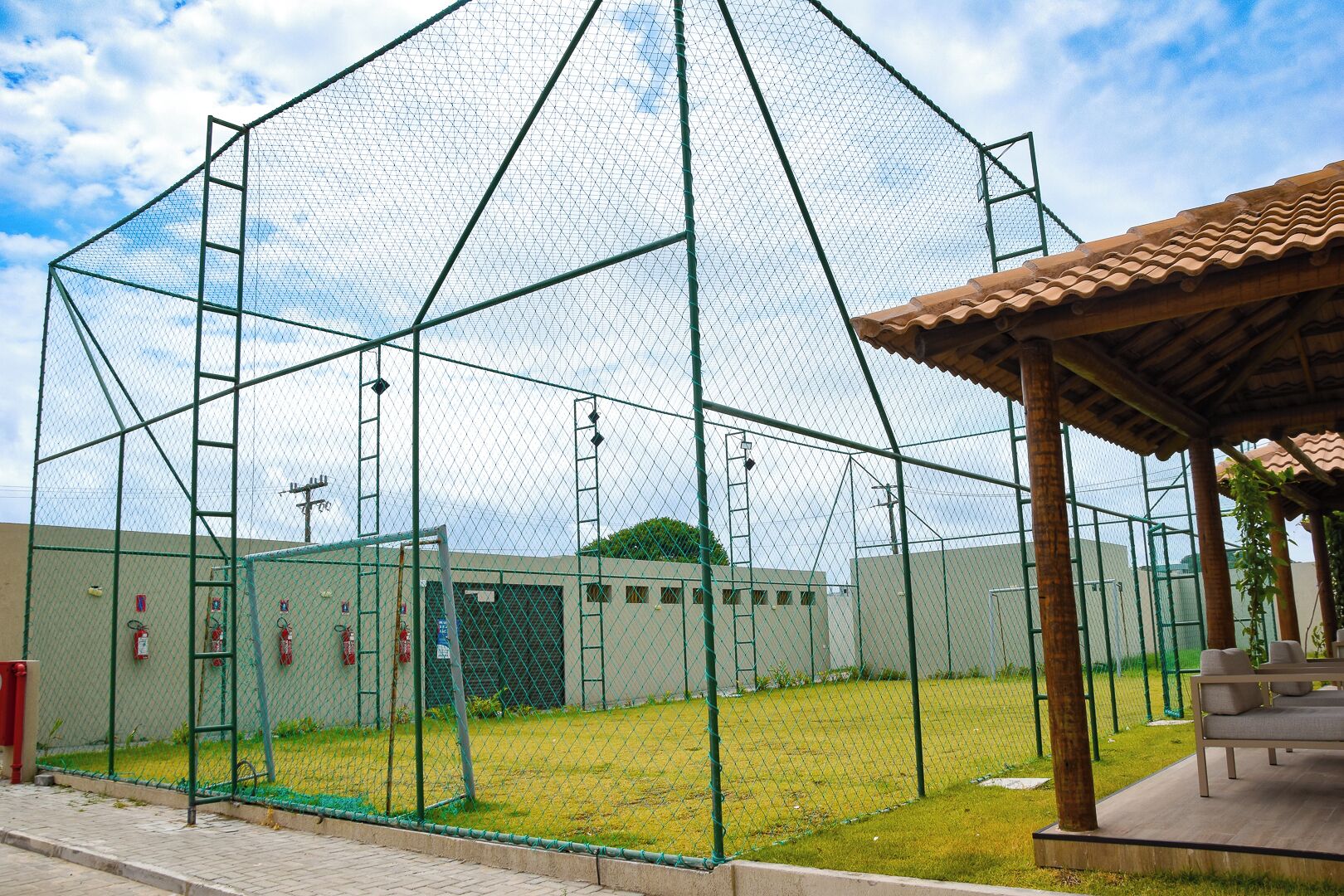 A fenced sports facility with a covered seating area.