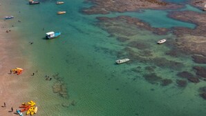 An aerial view of a beach with clear turquoise waters, boats, and kayaks. - Studio 5.0 ★ | Condo with Pool + Hot Tub | 5 min from Brazil's most famous beach (Tamandaré)