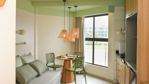 A compact living space with a sofa, dining table, chairs, and a kitchen area. - Studio 5.0 ★ | Condo with Pool + Hot Tub | 5 min from Brazil's most famous beach (Tamandaré)