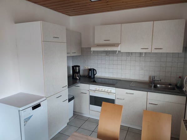 A compact kitchen with white cabinets, a built-in oven, a coffee maker, and a sink. - Quietly located vacation apartment (Altensteig)