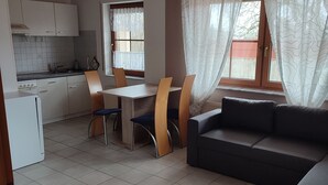 Un espacio habitable compacto con kitchenette, un comedor con mesa y sillas, y un sofá.
