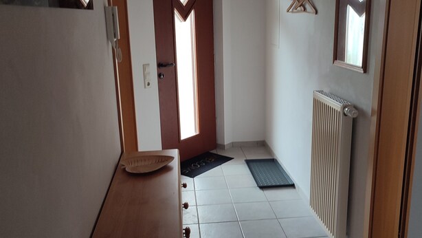 Un pasillo con una puerta de madera, un radiador y un ventanal pequeño.