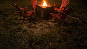 A square fire pit with a fire burning in the center, surrounded by four red Adirondack chairs. - Acadia Coastal Cape 20 min to Acadia National Park (Lamoine)