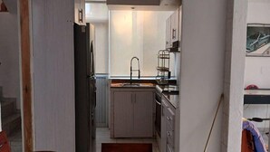 Une cuisine compacte avec une table à manger en verre, un évier et des placards.