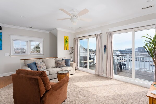 A spacious living room with a large window, a ceiling fan, and a view of the water.