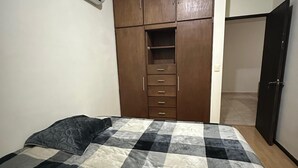 Une chambre à coucher comprenant un lit, une armoire et un appareil de climatisation.