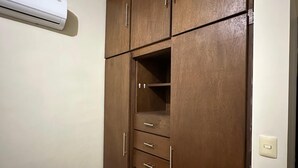 Une chambre avec une armoire en bois, un lit et un appareil de climatisation.