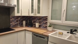 Ett modernt kök med vita skåp, en inbyggd ugn, en spis och en diskmaskin.