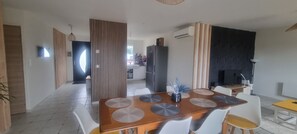 Un espace repas moderne avec une table en bois, des chaises blanches et une cuisine en arrière-plan.