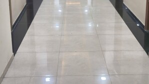 A long, well-lit hallway with doors on both sides, leading to individual rooms. - Omex Hazratganj (Lucknow)
