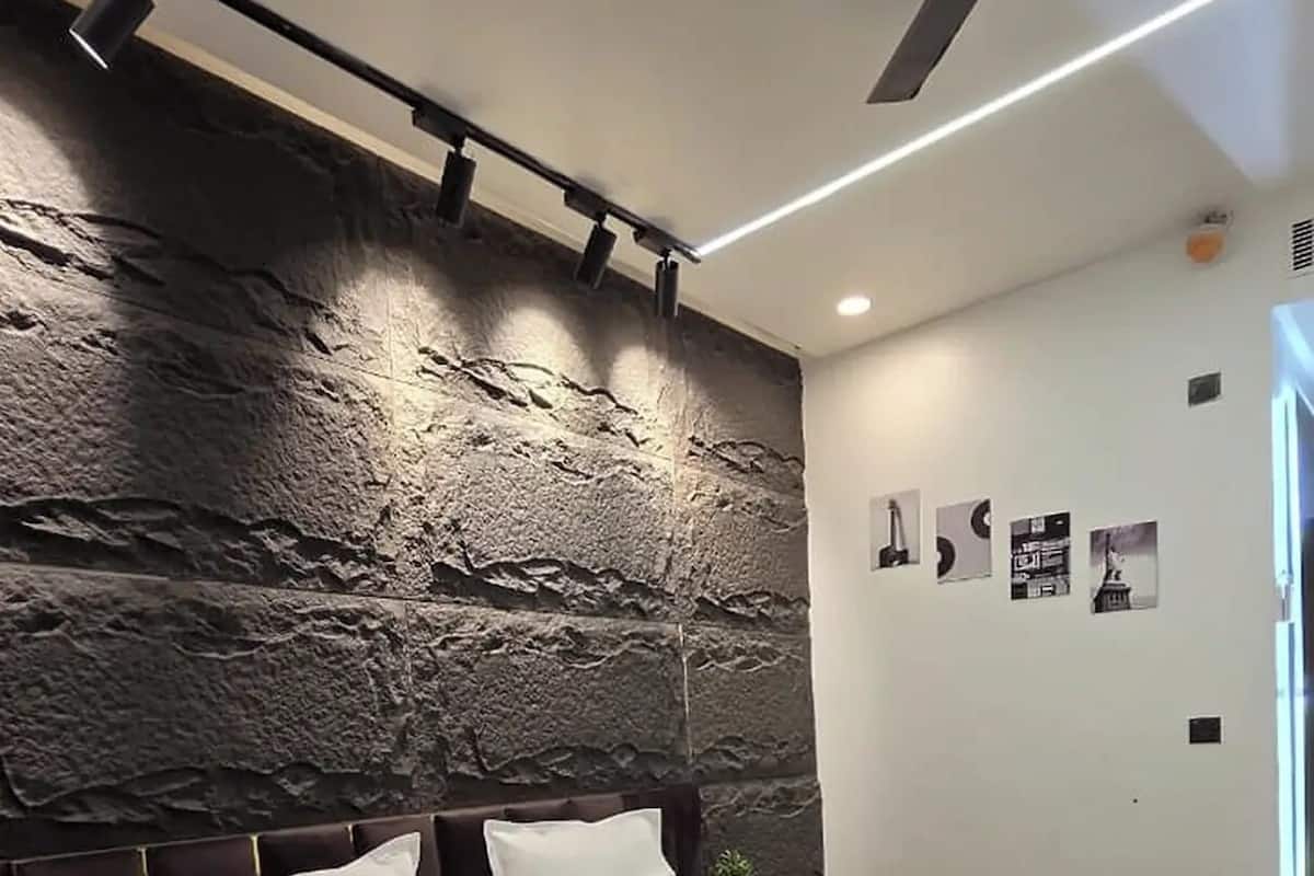 Ein modernes Schlafzimmer mit einem großen Bett, einem Deckenventilator und einer strukturierten Wand.