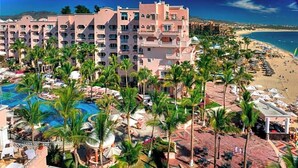 Un resort con piscina, palmeras y una playa.