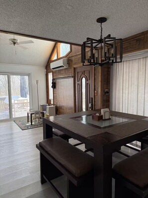 A spacious room with a large dining table, a ceiling fan, and a modern chandelier. - Cozy Mountain Escape-Poconos-Four Season Amenities-Game Room-Fire Pit-Hot Tub (Bushkill)