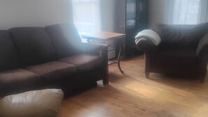 Una sala de estar con un sofá de cuero marrón, un sillón beige y una mesa de centro de madera.