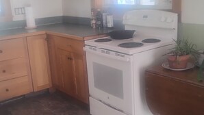 Una cocina con armarios de madera, una estufa blanca y un ventanal.