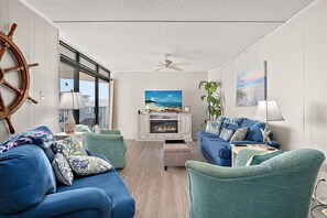 Ein Wohnzimmer mit Kamin, zwei Sofas, einem Fernseher und einem Deckenventilator.