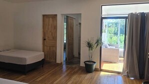 A room with a bed, a potted plant, and a view of the outdoors through a sliding door. - Quesada House (Tamarindo)