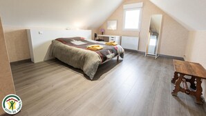 Een slaapkamer met een bed, een bureau, een stoel en een klein tafeltje.
