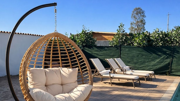 A hanging chair, lounge chairs, and a poolside setting. - HOTEL LARIMAR - Valle de Guadalupe (Valle de Guadalupe)