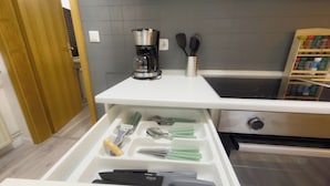 Een keuken met een koffiezetapparaat, spatels en een rekje met kruiden.