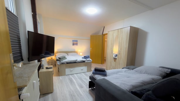 Een moderne slaapkamer met een bed, een bank, een kledingkast en een televisie.