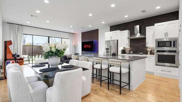 A modern kitchen with white cabinets, a central island, and a built-in microwave. - Oak Lawn Escape | Short Drive to Fair Park (Dallas)