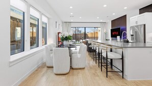 A modern kitchen with a bar area, white cabinetry, and a large window. - Oak Lawn Escape | Short Drive to Fair Park (Dallas)