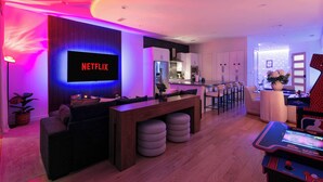 A modern living room with a Netflix TV, a gaming console, and a bar area. - Trendy Oak Lawn Retreat | Near Fair Park (Dallas)