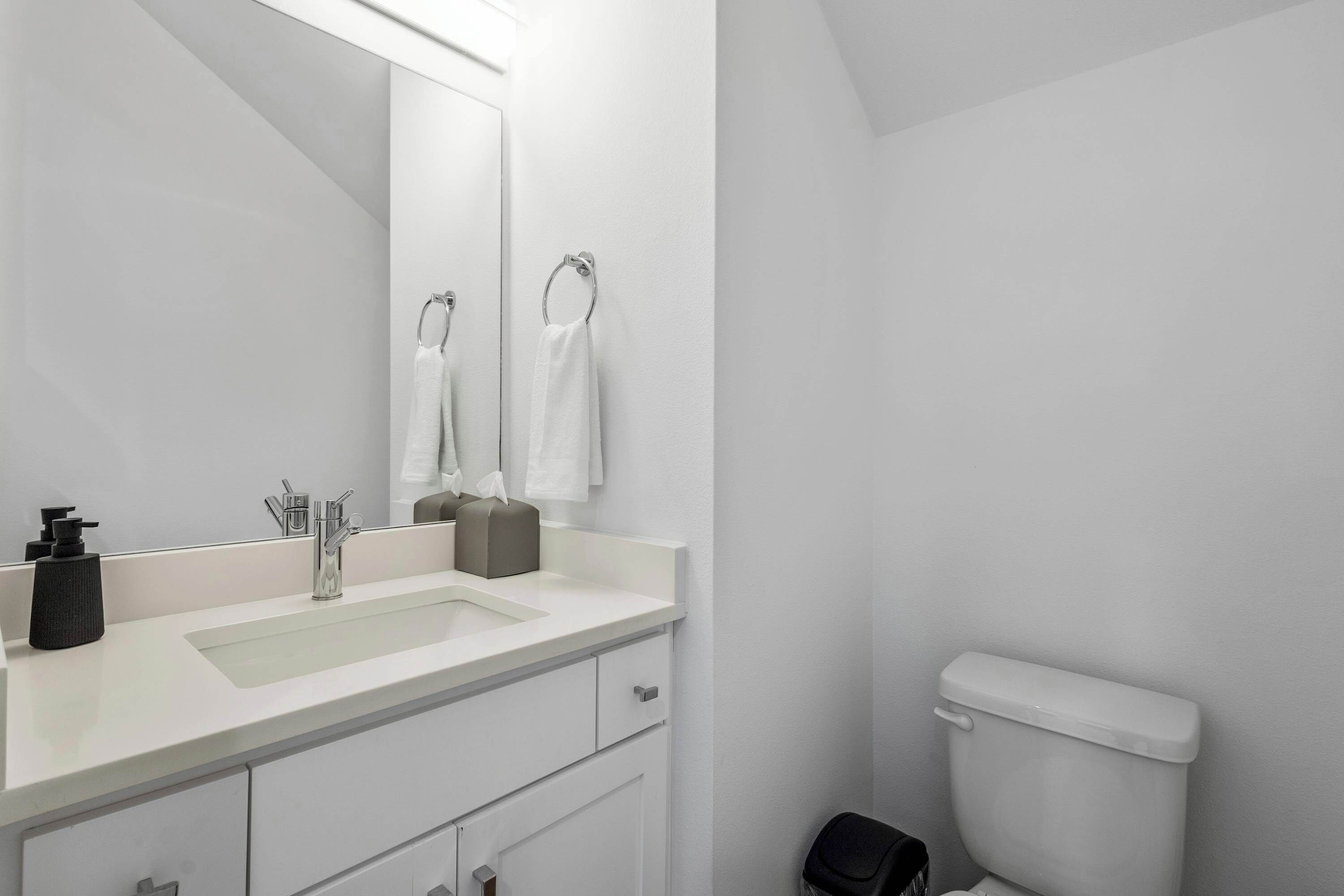 Ein modernes Badezimmer mit Waschbecken, Spiegel und Toilette in Weiß.