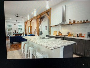 A modern kitchen with a central island, wooden beams, and a staircase leading to an upper level. - "Loo-vul" Retreat - Pool Table • Chill Vibes (Louisville)