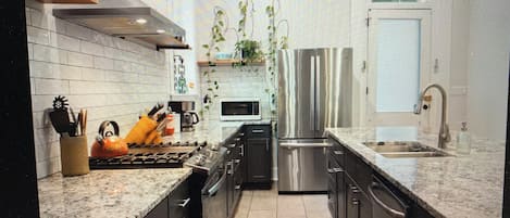 Cocina moderna con electrodomésticos de acero inoxidable, un microondas y un fregadero.