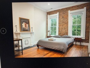 A bedroom with a brick wall, a fireplace, a bed, and two windows. - "Loo-vul" Retreat - Pool Table • Chill Vibes (Louisville)