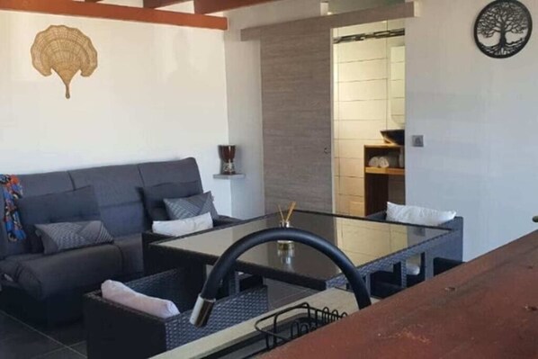 Un espace de vie moderne comprenant un canapé, une table avec un plateau en verre et un élément décoratif mural.