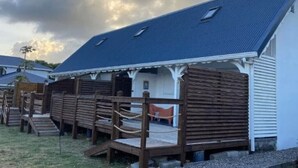 Een gebouw met een schuin dak, houten hekken en een klein terras.