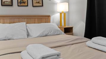 Un lit bien fait, avec des draps blancs, une tête de lit en bois et une lampe de chevet.