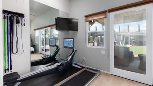A home gym with a treadmill, exercise equipment, a TV, and a large mirror. - Luxury Wine Country Casita with Extraordinary Ridgetop Views Extensive Amenities (Fallbrook)