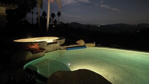 A swimming pool with a moonlit night sky, palm trees, and distant city lights. - Luxury Wine Country Casita with Extraordinary Ridgetop Views Extensive Amenities (Fallbrook)