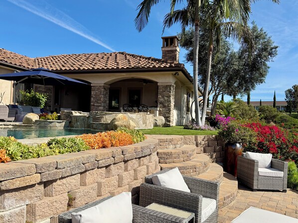 Una casa con piscina, muebles de exterior y un jardín bien cuidado.