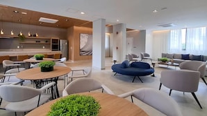 Un hall d’hôtel moderne comprenant un espace repas, des sièges et un comptoir d’accueil.