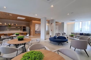 A modern hotel lobby with a dining area, seating, and a reception desk. - Luxurious studio apartment in a prime location. (São Paulo)