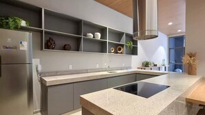Une cuisine moderne dotée d’un îlot central intégré, de meubles de couleur grise et d’un réfrigérateur en acier inoxydable.