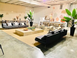 A spacious living area with a sectional sofa, a coffee table, and potted plants. - Art Foundry Pickleball Basketball pingpong 10ksqft 10 bedroom sleeps 40 (East Point)