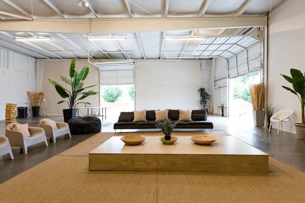 Una sala moderna con un sofá, sillas, una mesa de centro y plantas en macetas.