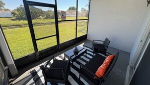 A balcony with a view of a grassy field and a warning sign. - Comfort Meets Magic: Cozy Home Near Disney! (Orlando)