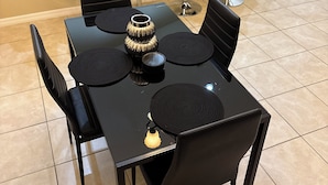 A dining area with a black table and chairs, a decorative bowl, and a small plant on the counter. - Comfort Meets Magic: Cozy Home Near Disney! (Orlando)