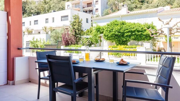 A balcony with a table and chairs, overlooking a residential area with trees and buildings. - Apartament Antic Plankton - Sa Riera Begur - Free Parking, Beach, Wifi, holidays (Sa Riera)