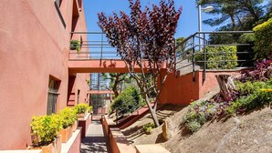 A narrow pathway flanked by red walls, leading to a building entrance with a metal staircase. - Apartament Antic Plankton - Sa Riera Begur - Free Parking, Beach, Wifi, holidays (Sa Riera)
