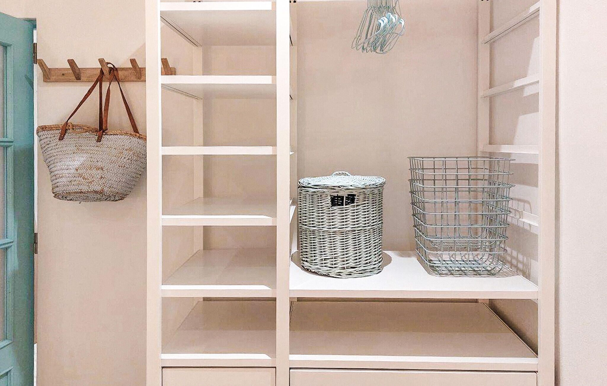 A white closet with shelves, a wicker basket, and a metal basket.