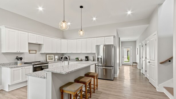 A modern kitchen with white cabinets, a stainless steel refrigerator, a granite countertop, and wooden stools. - Charming 3-bedroom Villa with garage in Madison-sleeps 10 (Madison)