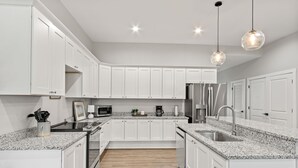 A modern kitchen with white cabinets, granite countertops, stainless steel appliances, and pendant lighting. - Charming 3-bedroom Villa with garage in Madison-sleeps 10 (Madison)